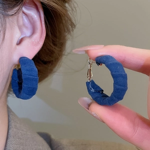 Detailed close-up of retro blue velvet circular earrings showing soft fabric texture