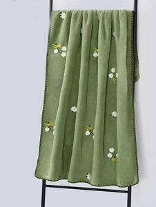 Detail of coral fleece towel featuring white daisy embroidery and a yellow bow accent