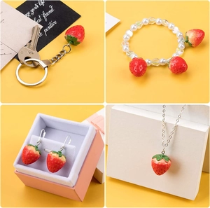 Flat lay of resin strawberry jewelry set with necklace, earrings, and pearl bracelet