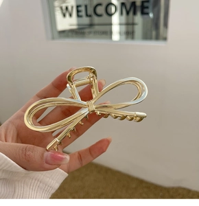 Detail of elegant gold metal bow hair claw clip showing strong spring and fine teeth