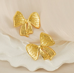 Détail macro de boucles d'oreilles nœud dorées avec texture élégante en métal brossé