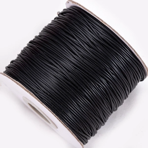 Detailed view of black waxed cord on white spool for DIY jewelry and leather sewing