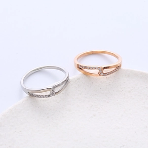 Detail of silver and rose gold intertwined rhinestone rings on a minimalist white disk