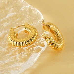 Detailed view of 18K gold plated twisted hoop earrings on textured glass and satin