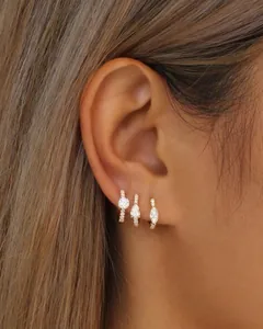 Detail shot of three gold huggie earrings with round, pear, and marquise cut zircon charms