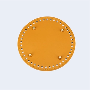 Detail of 15cm round PU leather bag base with pre-punched holes and gold metal feet