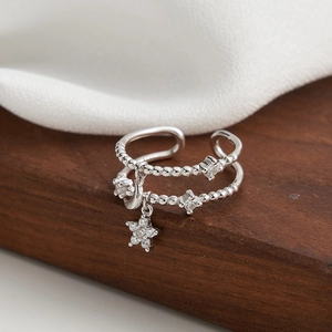 Close-up of double layer silver ring with star pendant and zircon on wood and silk