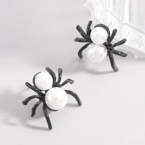 Macro detail of gothic spider earrings featuring white faux pearls on black metal