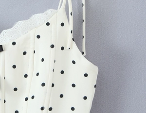 Detail of white polka dot dress featuring delicate lace trim and thin shoulder straps