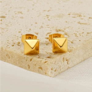 Vue macro de boucles d'oreilles pyramides en or 18k sur un socle en pierre