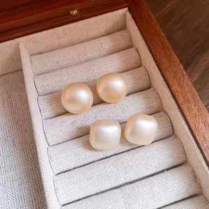 Close-up of champagne matte pearl earrings in geometric round and square shapes