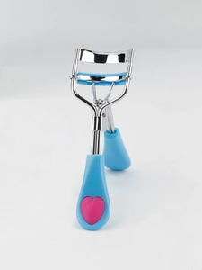 Macro shot of eyelash curler with blue comb pad and pink heart handle decoration