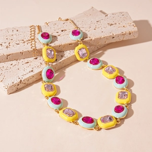 Detail of colorful geometric enamel necklace with rhinestones on beige stone