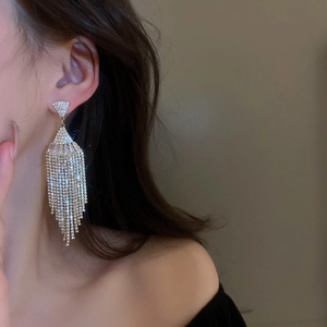Close-up of model wearing fan-shaped tassel earrings with pavé rhinestones and gold plating