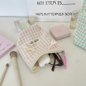 Detailed view of pink plaid cosmetic bag with small bows and tassel zipper pull