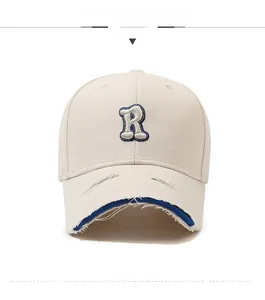 Close-up of beige baseball cap with R letter embroidery and distressed brim detail
