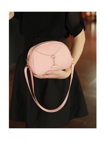 Detail of pink chevron quilted shell bag with twin pearl charms held by model