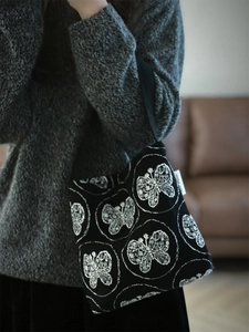 Close-up of fine white butterfly embroidery on a black canvas mini hobo bag