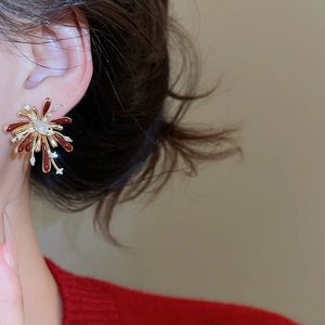 Detail shot of vintage style gold fountain earrings with red enamel and clear zircons