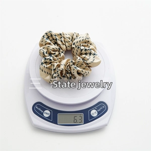 Detail showing the 6.3g lightweight satin scrunchie with classic houndstooth pattern