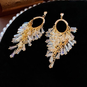 Elegant gold fringe earrings with oval crystals and diamonds on a black velvet background