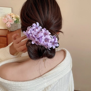 Detailed view of lavender fabric flower hair clip styled on an elegant bun hairstyle
