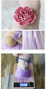 Detail view of plush faceless gnome doll featuring purple beard and pink flower decorations