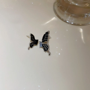 Detailed macro view of butterfly earrings with black enamel and blue zircon stones