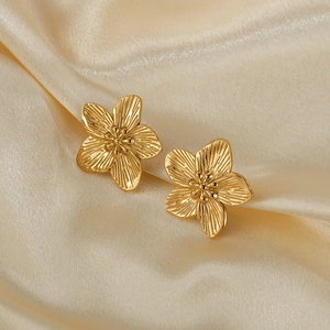 Macro shot of French vintage gold-plated floral earrings on champagne silk fabric