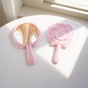 Close-up of pink rose-shaped handheld mirror showing relief flower design and reflective glass