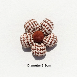 Close-up of a 5.5cm brown houndstooth fabric flower accessory with padded 3D texture