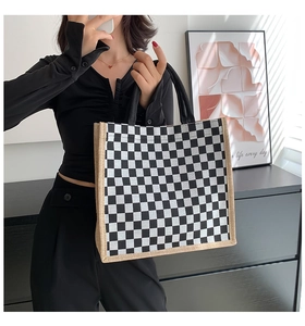 Detail shot of checkered linen tote bag with jute trim held by a model in a modern room