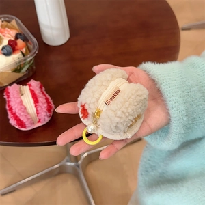 Detail of plush macaron pouch with white fur texture, pearl charm, and yellow ring hook