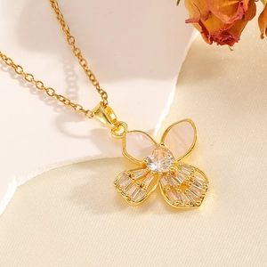 Elegant gold bow necklace with heart stones and shell inlays on a decorative stone base