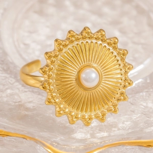 Vintage 18k gold plated sunburst ring with central pearl on a glass textured surface