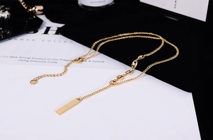 Macro shot of 18K gold plated polished bar pendant and fine chain necklace for women