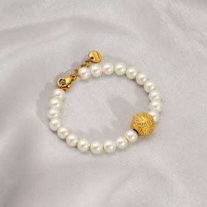 Detail of a handmade shell pearl bracelet with gold clasp on white silk background