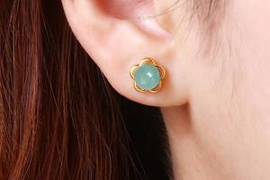 Detail of flower-shaped silver stud earring with green aventurine stone on ear