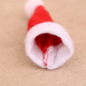 Close-up of a mini red felt Christmas hat with a white plush pompom and rim