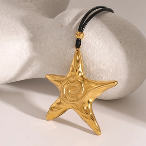 Macro detail of a 18k gold starfish pendant with hammered texture on black wax rope