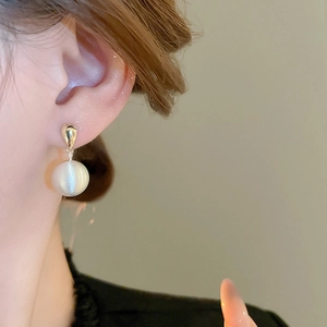 Détail d'une élégante boucle d'oreille dorée avec une perle ronde sur mannequin