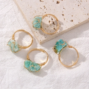 Detail of four handmade gold wire-wrapped rings with irregular natural green gemstones