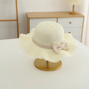 Detail of off-white woven straw hat with wavy lace brim and polka dot ribbon bow
