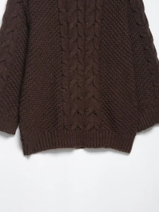 Detail of chunky cable knit pattern and ribbed cuffs on a brown oversized sweater
