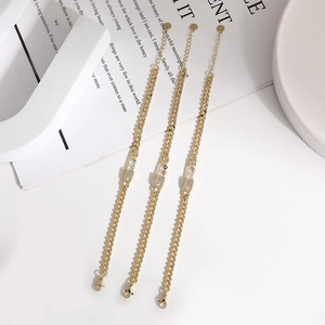 Detail of paperclip bracelets with evil eye charms and micro-set zirconia in gold finish