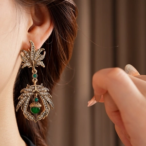 Detail of vintage leaf earrings with green gemstone and small diamonds on model