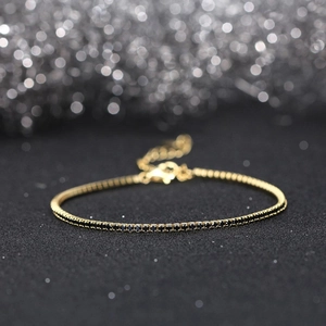 Close-up of gold-plated silver tennis bracelet with micro-paved black zircons and toggle chain