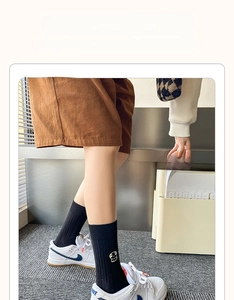 Detail of black rib-knit socks with cream puppy embroidery and high elastic fiber
