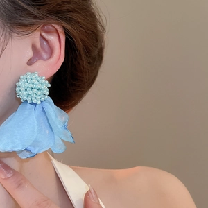 Detail of light blue beaded flower earrings with chiffon tassel on model's ear