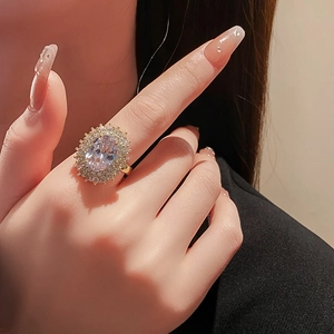Close-up of gold plated oval zircon ring with halo setting on a female model finger